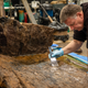 A conservator works on the oak coffin.